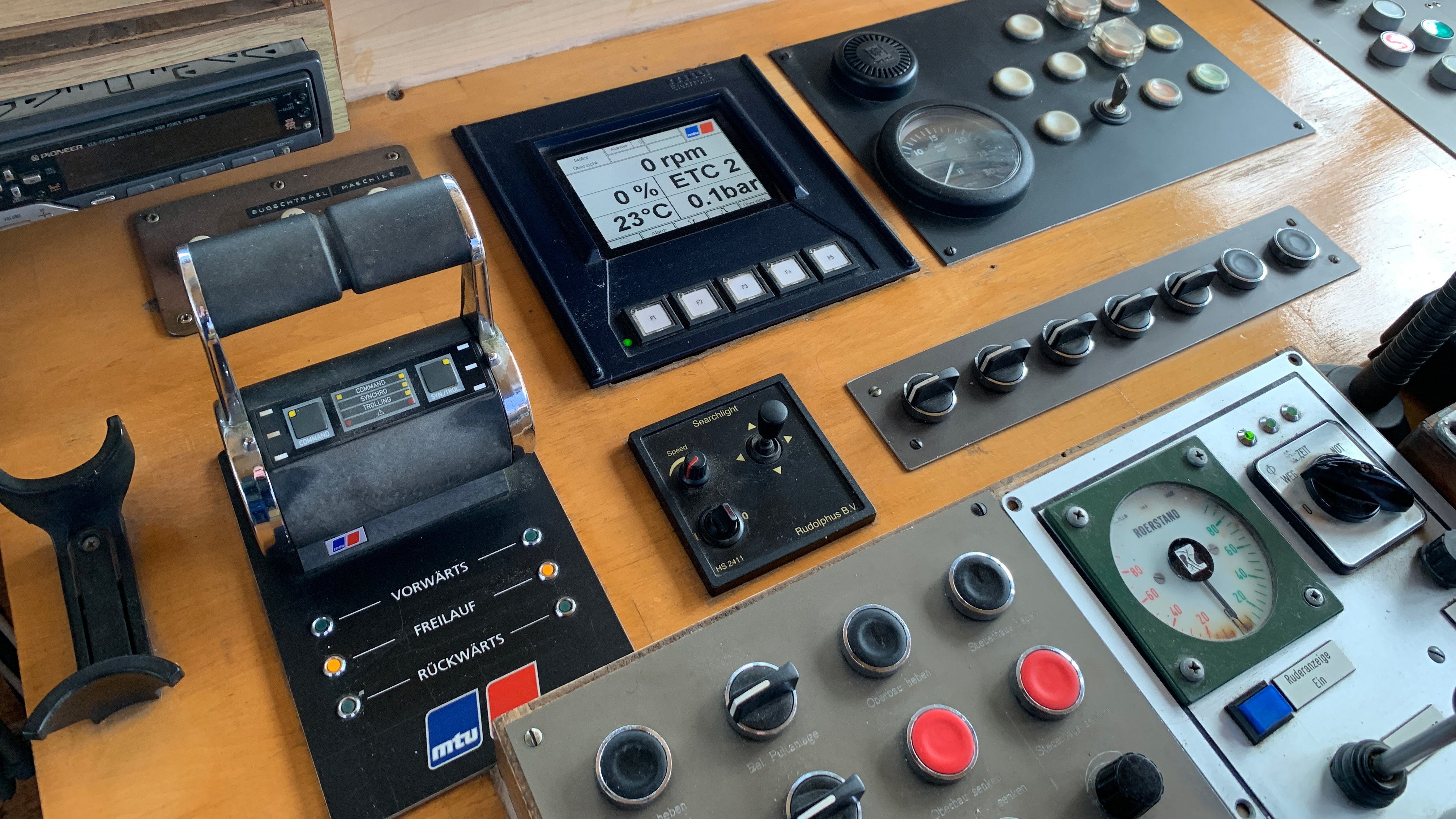 The image shows an old bridge panel with control lever, indicators and push buttons mounted on a wodden bridge console