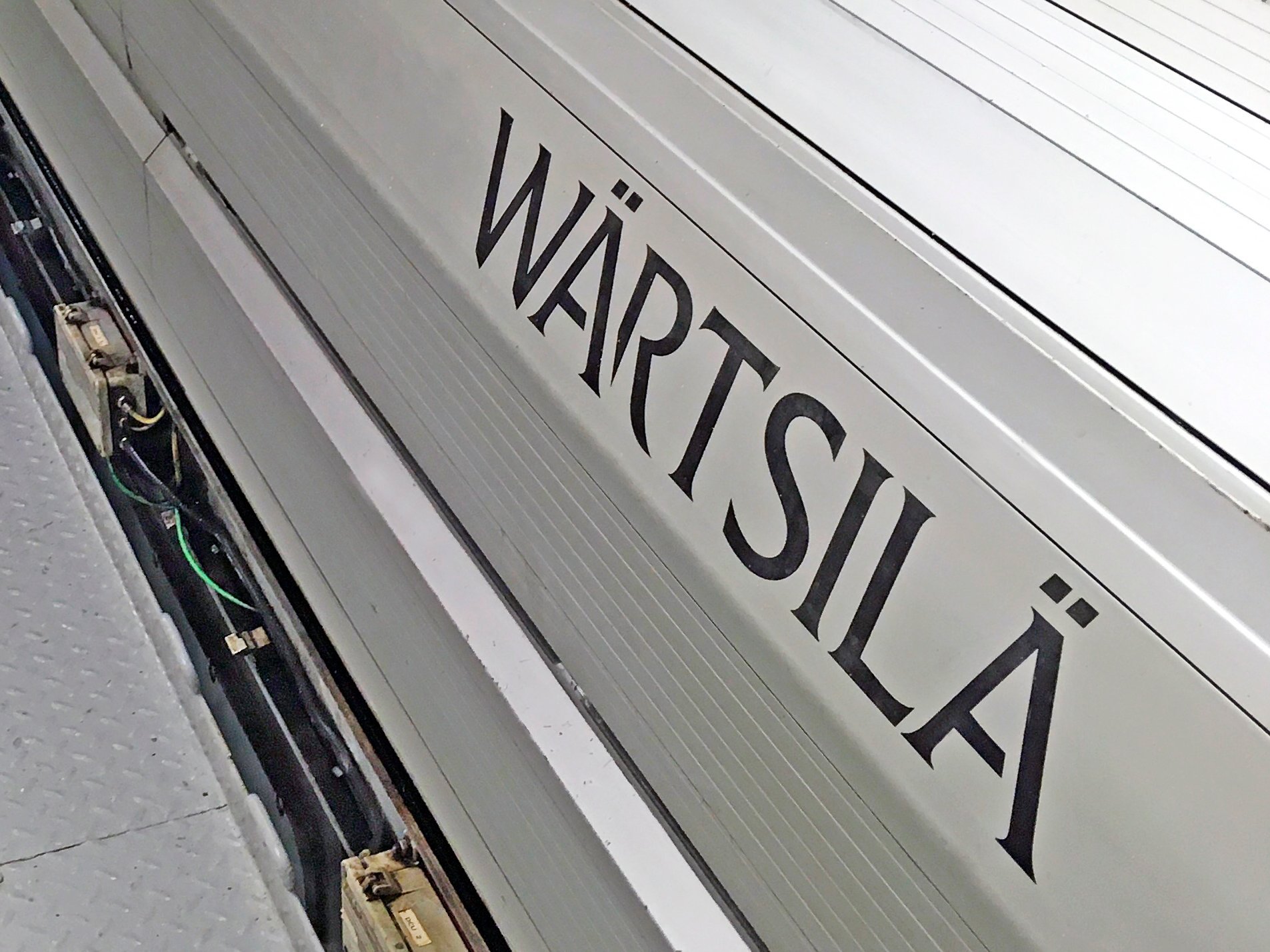 The image shows an engine room of a ship with a silver coloured WECS 23000 engine control system of Wärtsilä