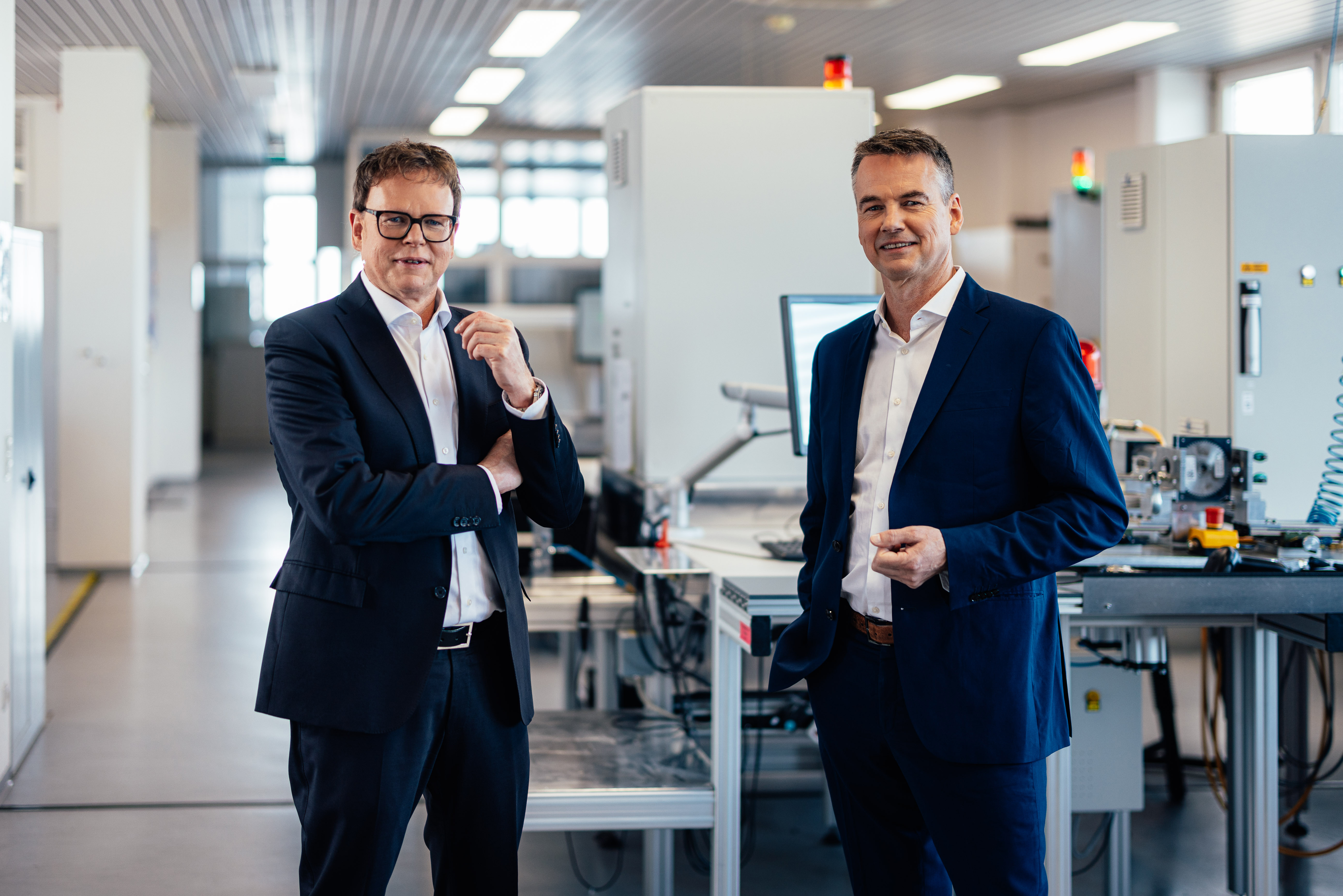 The image shows the sensor testing laboratory of Noris Group with the two managing directors Michael and Florian Schmidmer standing in front of a testing station