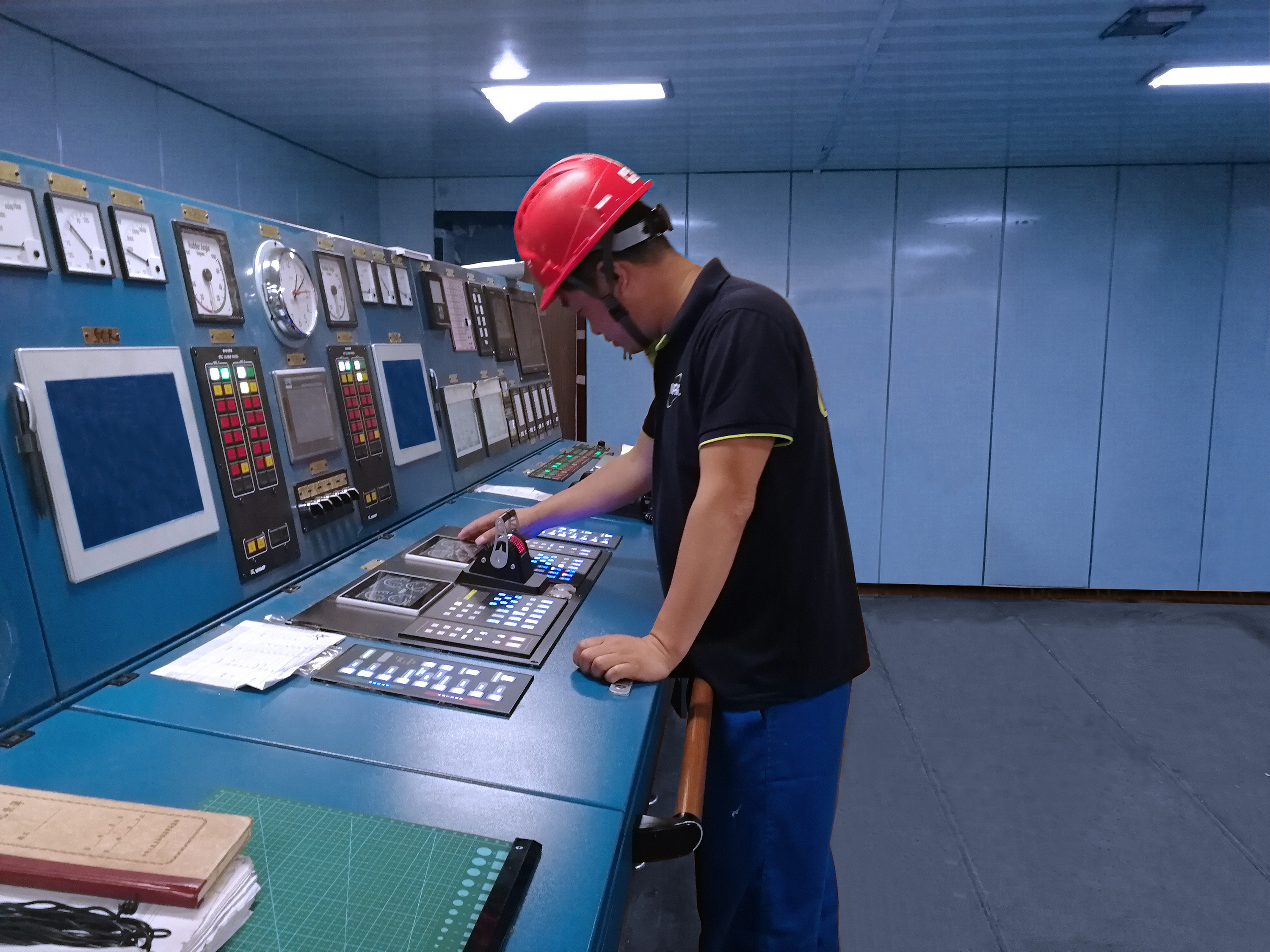 Das Bild zeigt einen Servicemitarbeiter von Noris in einem Maschinenkontrollraum mit blauen  Wänden. Er steht an einem Fahrhebelpaneel und prüft die Funktionalität.