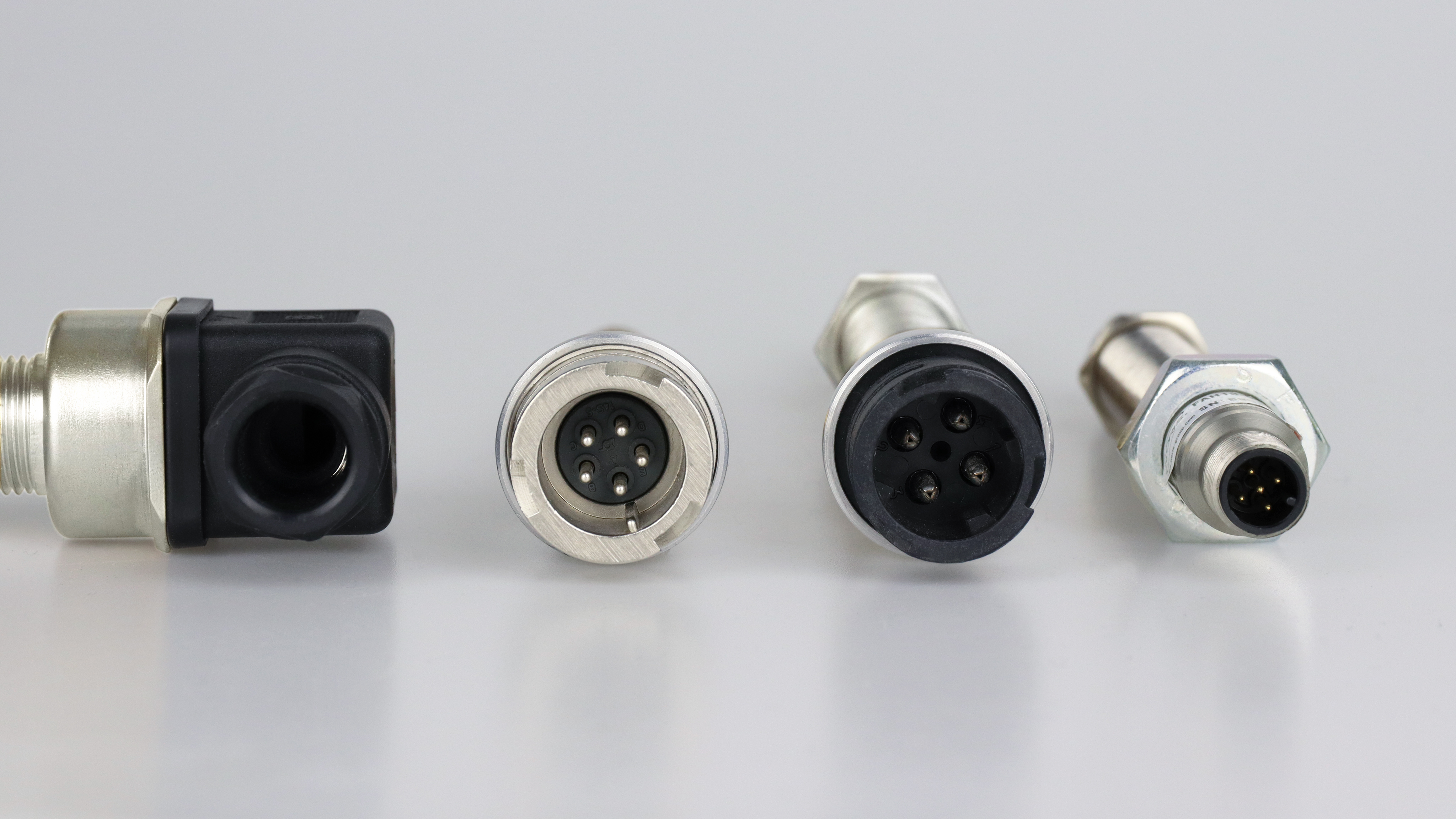 The image shows 4 connector plug  variants laying on a grey background